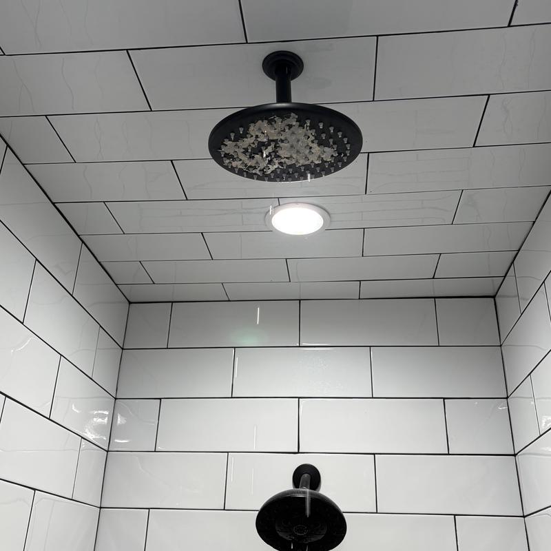 Showerhead and tub faucet with water flow in tiled shower Showerhead and tub faucet with water flow in tiled shower