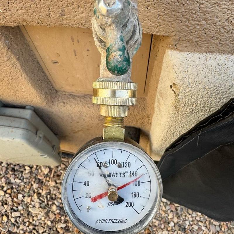 Pressure gauge on outdoor water faucet near meter box