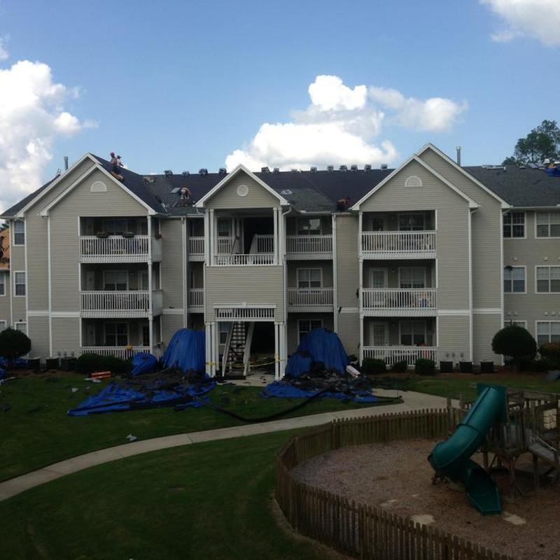 Apartment complex roof replacement with tarps and workers