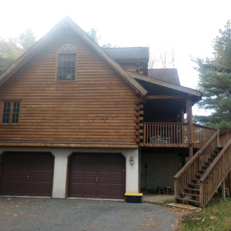 Log cabin roof inspection with attached garage and deck
