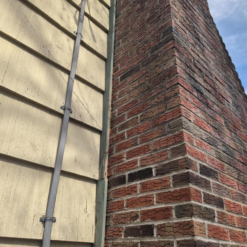 Brick chimney exterior with mortar and siding nearby Brick chimney exterior with mortar and siding nearby