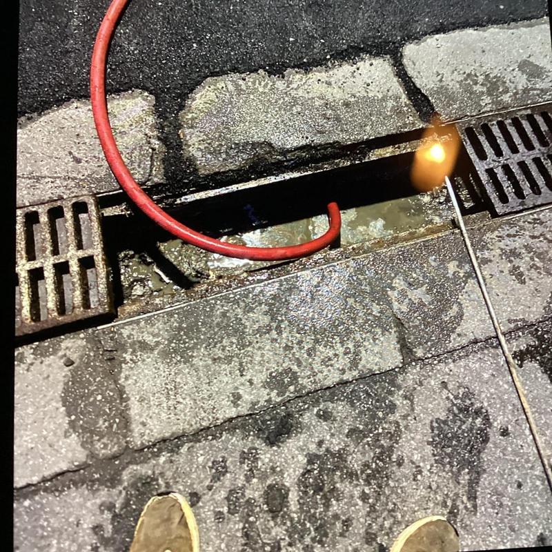 Drain grate and pipe with cleaning snake in pavement