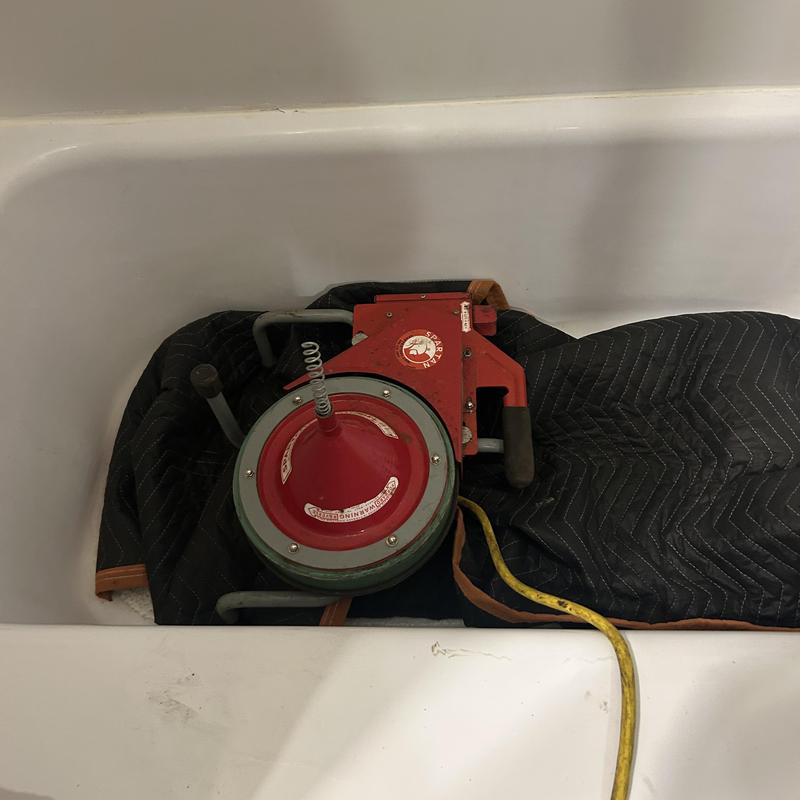 Bathtub drain cleaning machine inside tub in bathroom Bathtub drain cleaning machine inside tub in bathroom
