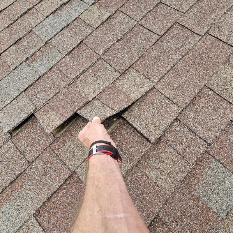 Asphalt roof shingles with hail damage lifted by hand