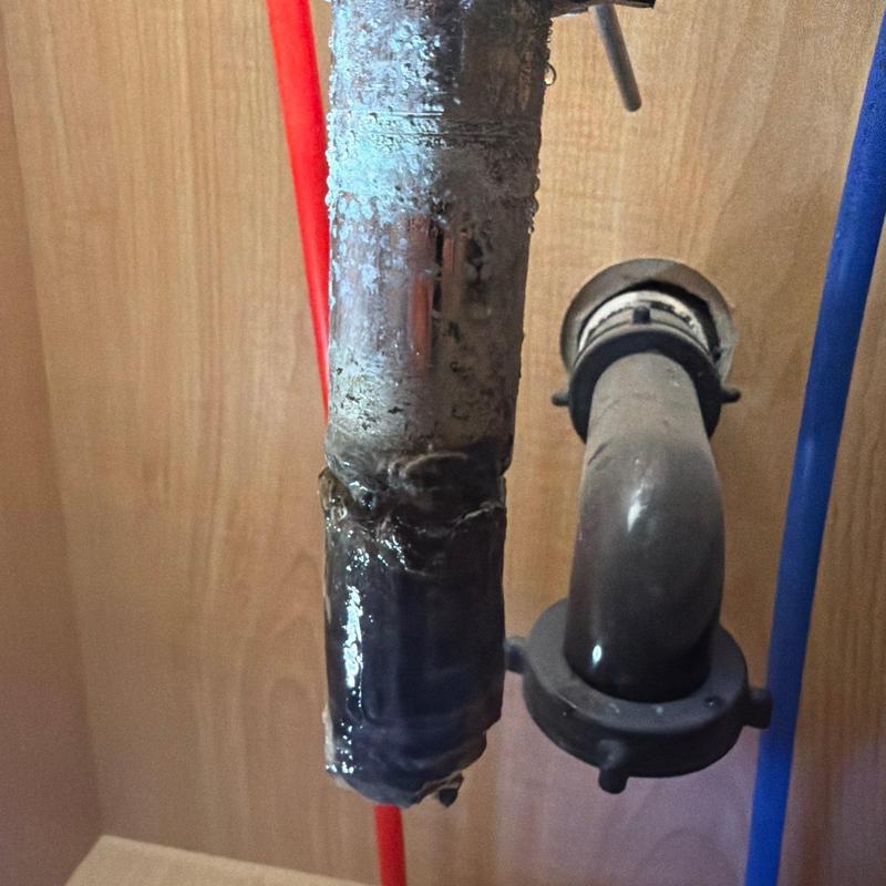 Metal drain pipe with removed clog and water droplets