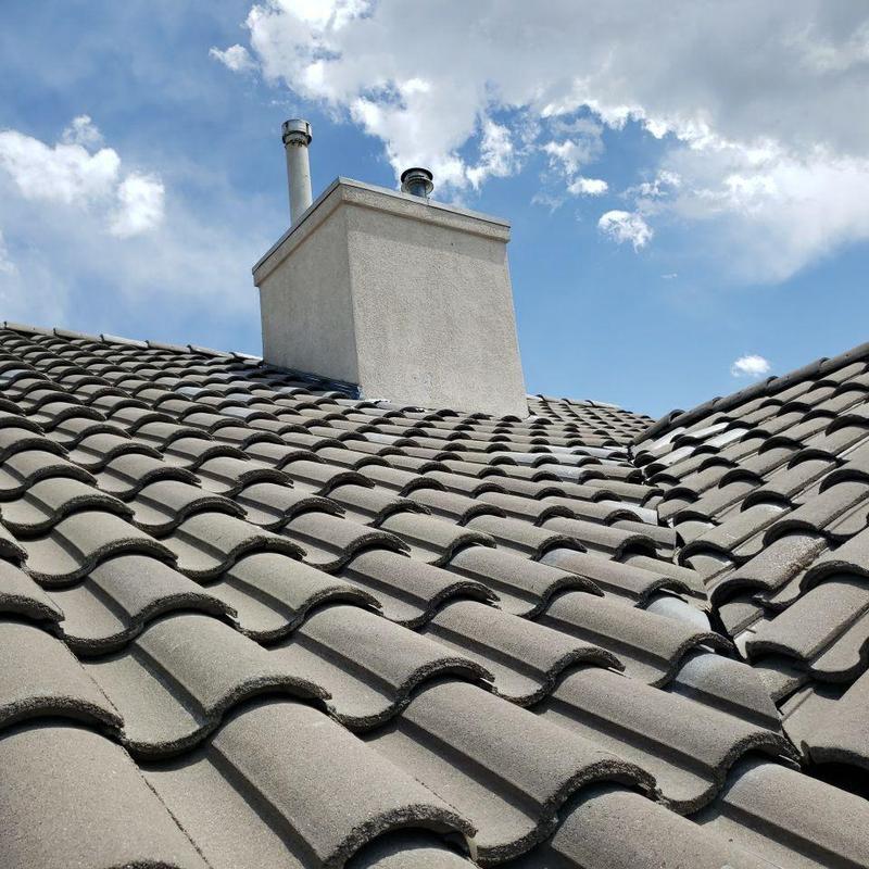 Chimney flashing on tile roof under blue sky