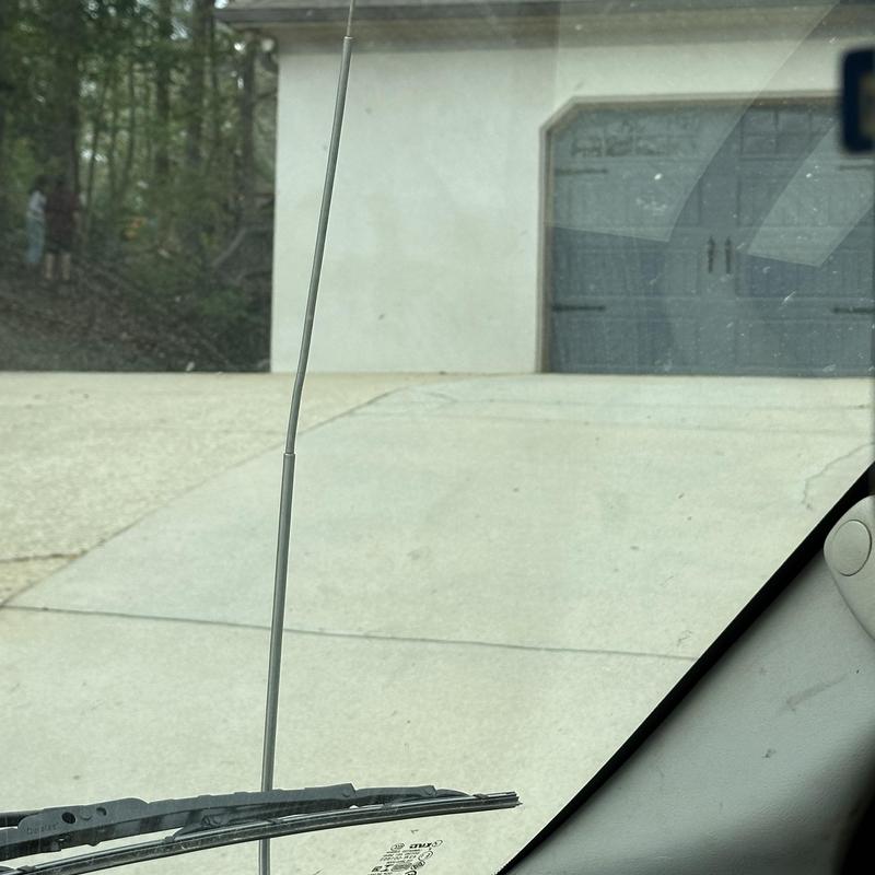 Outdoor hose bibb with vehicle antenna in foreground