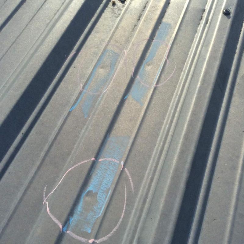 Metal roof panels with hail damage circled in chalk