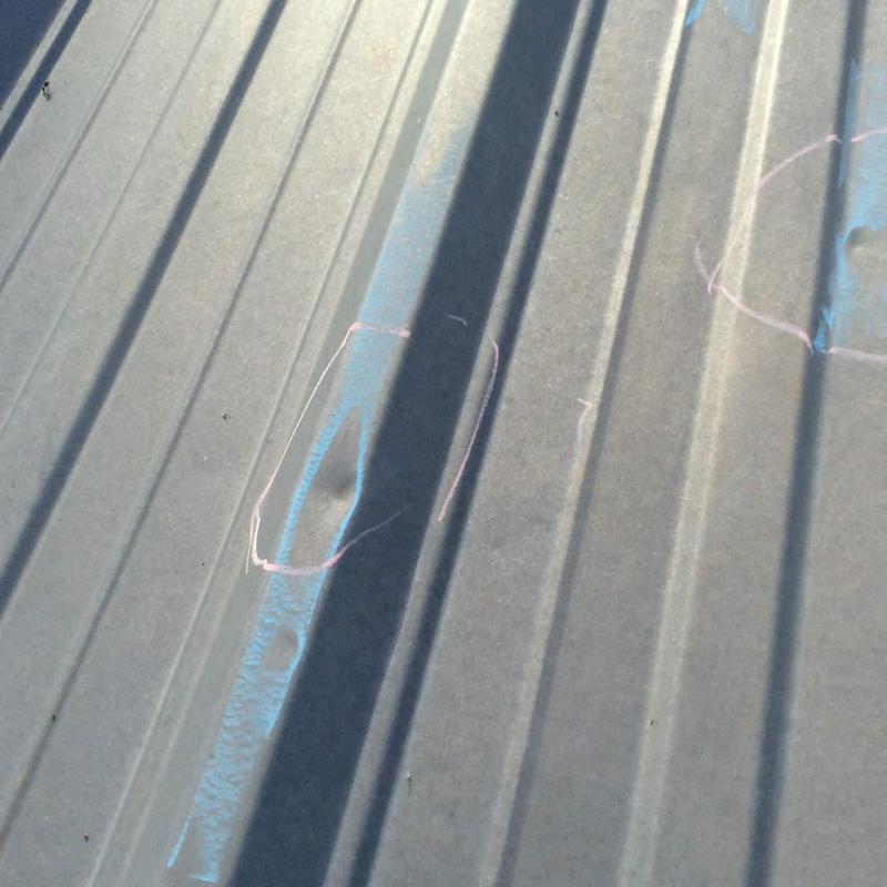 Metal roofing with hail damage marked for repair