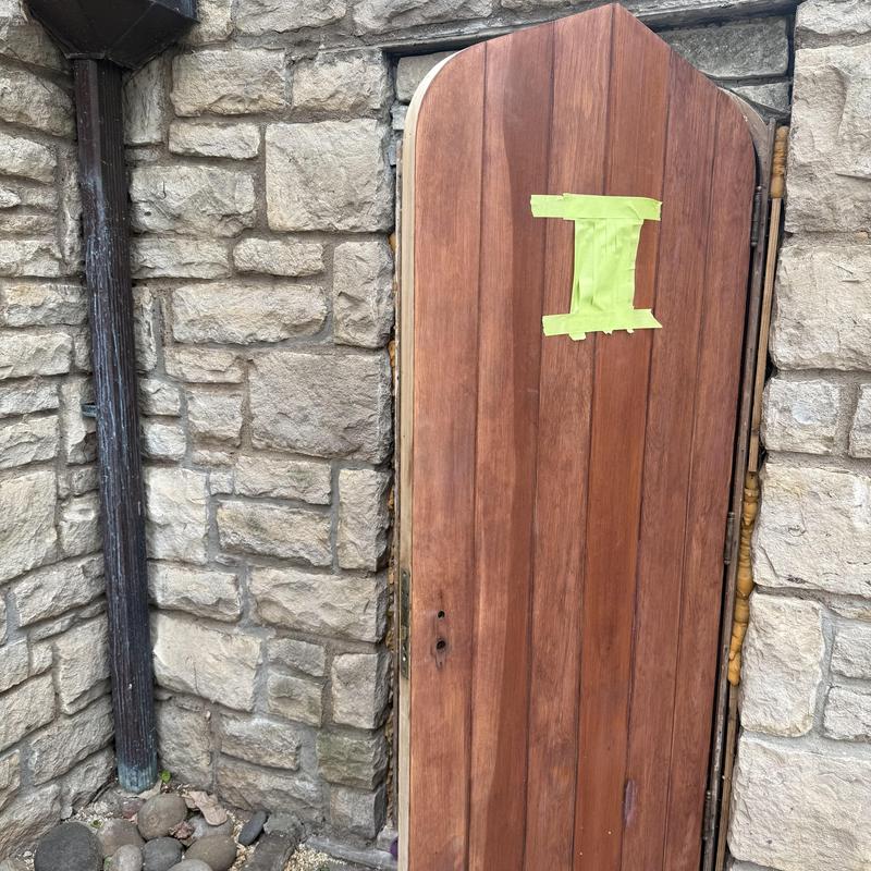 1930s wooden door with taped marking in stone wall