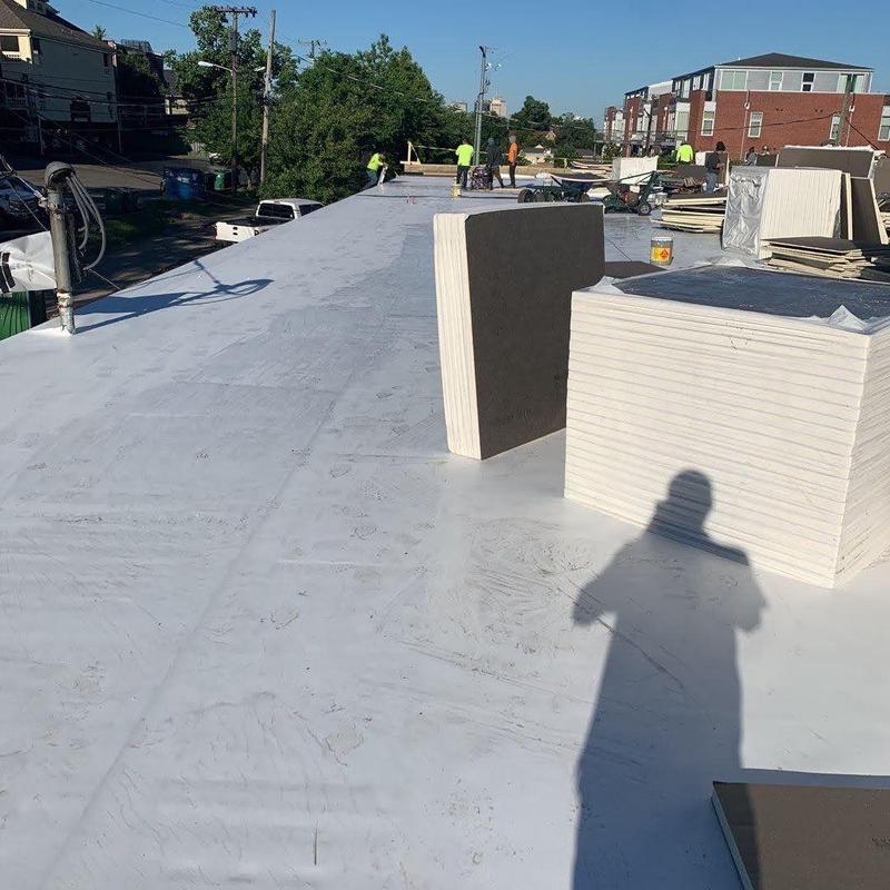 Commercial flat roofing with insulation panels and workers