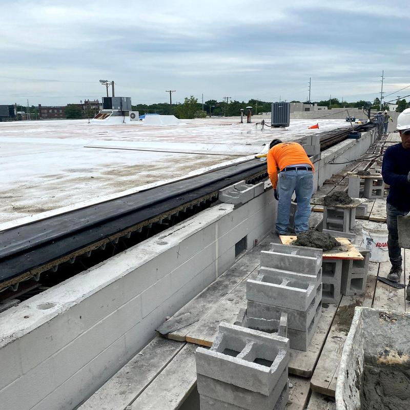 Commercial roofing edge with block wall and workers