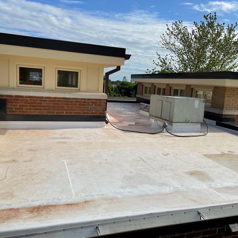 Flat roof membrane with rooftop HVAC unit and brick walls
