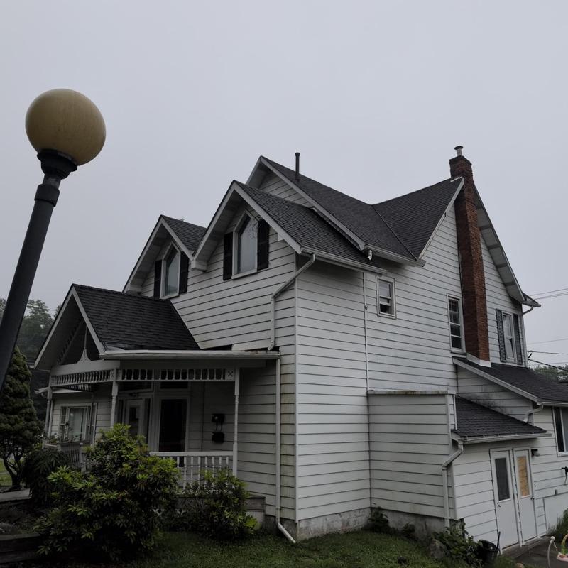 Asphalt shingle roof inspection on white house exterior