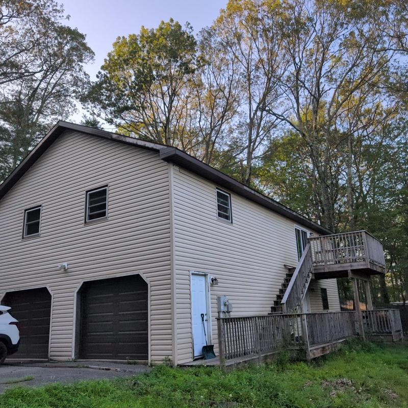 Vinyl siding exterior with attached wooden deck and stairs