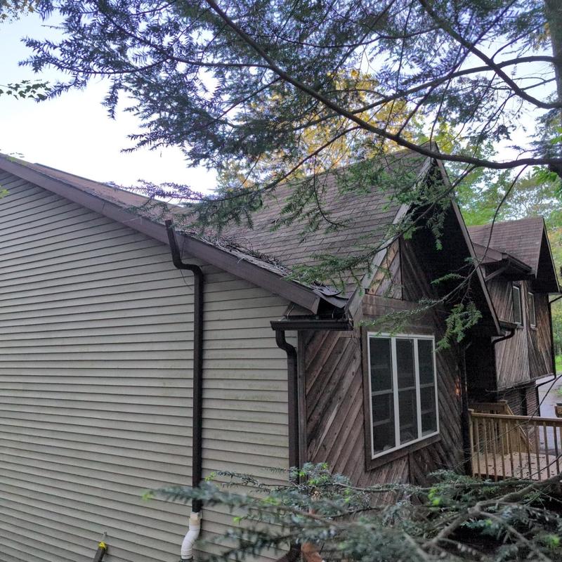 Asphalt shingle roof with gutter inspection on house exterior