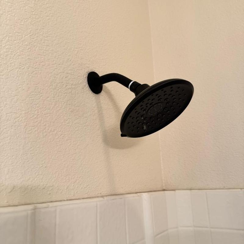 Black shower head and arm installed on wall