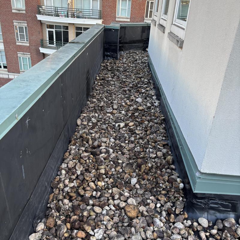 Ballasted roof system with stone gravel layer near wall