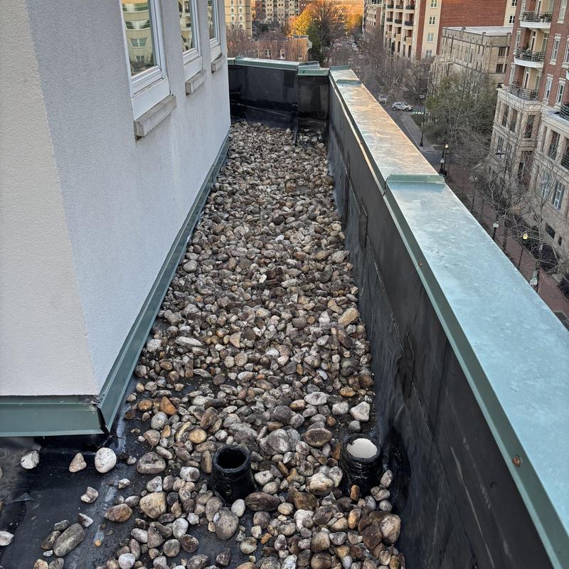 Gravel-covered roof drainage with exposed drain pipes