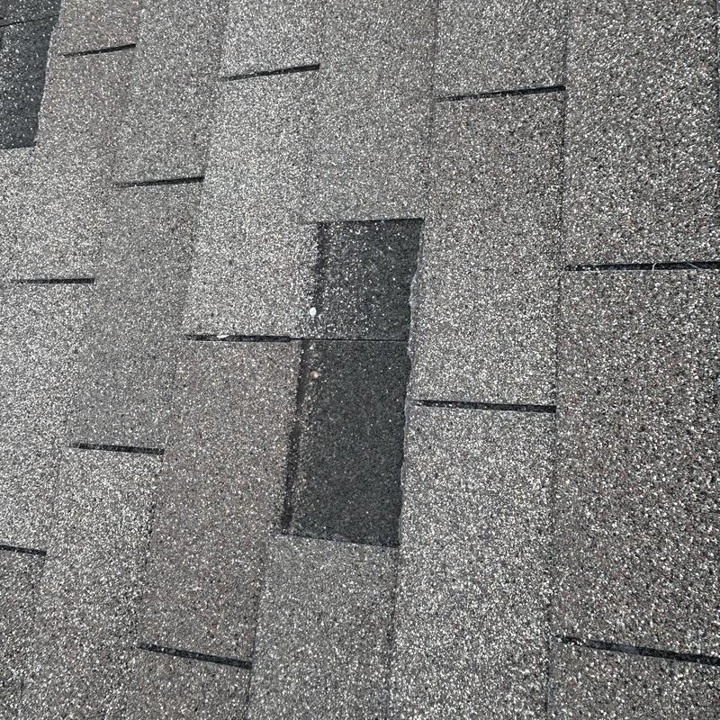 Asphalt shingles with a damaged missing shingle section