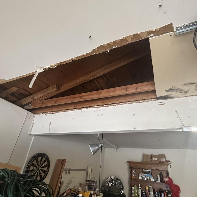 Garage ceiling with exposed wooden beams and damage