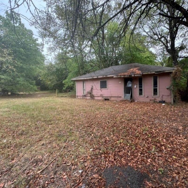 House exterior with worn roof and overgrown yard