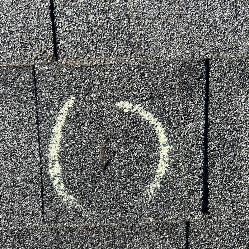 Asphalt shingle damage marked with chalk on roof surface