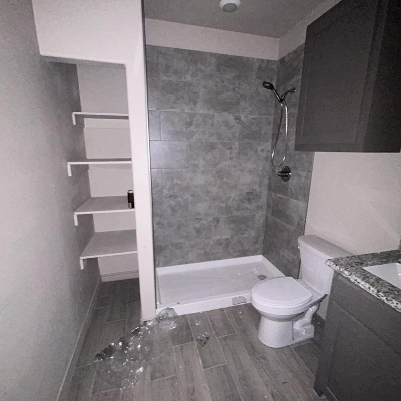 Bathroom shower with gray tile and white toilet