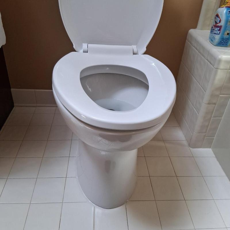 Toilet bowl with seat open in tiled bathroom