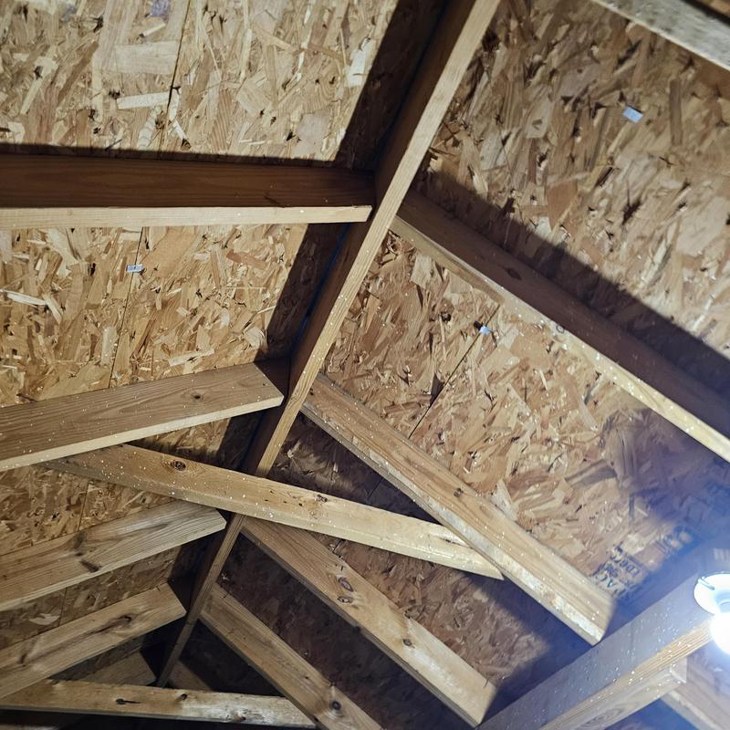 Roof sheathing with hail damage inside attic framing
