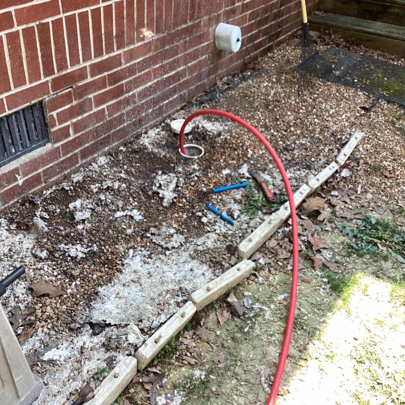 Jet drain cleaning with red hose outside brick wall