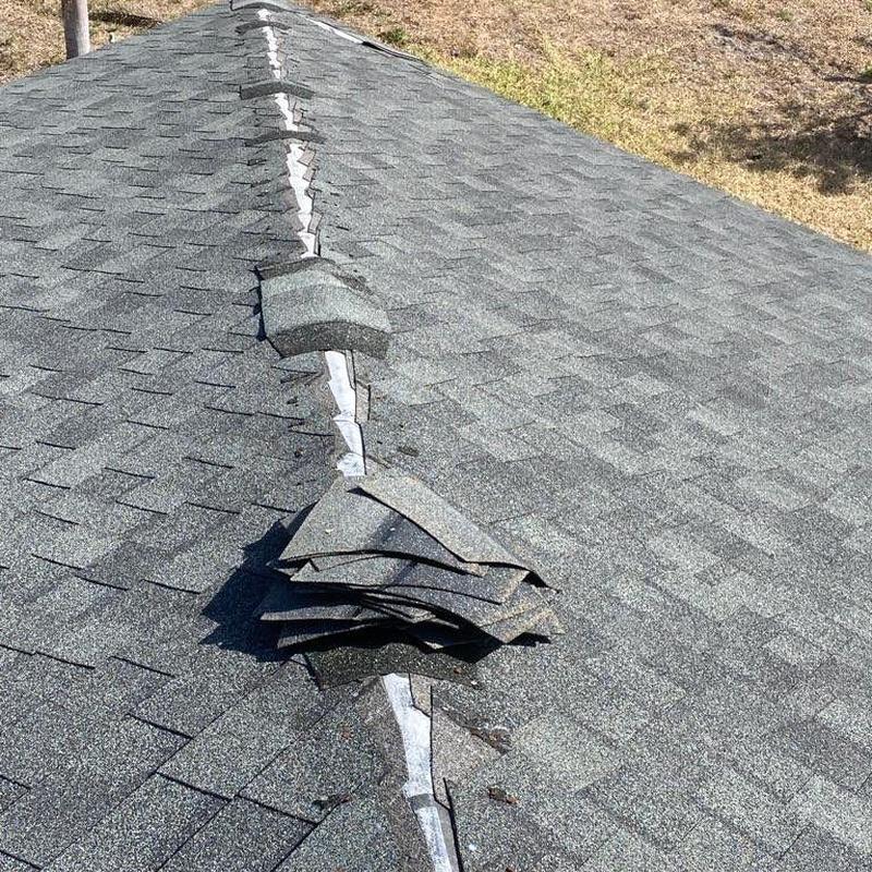 Shingle roof ridge with loose and damaged shingles