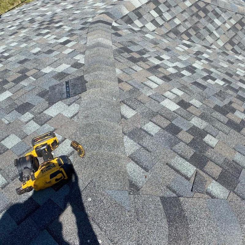 Hip cap shingles with power nailer on roof