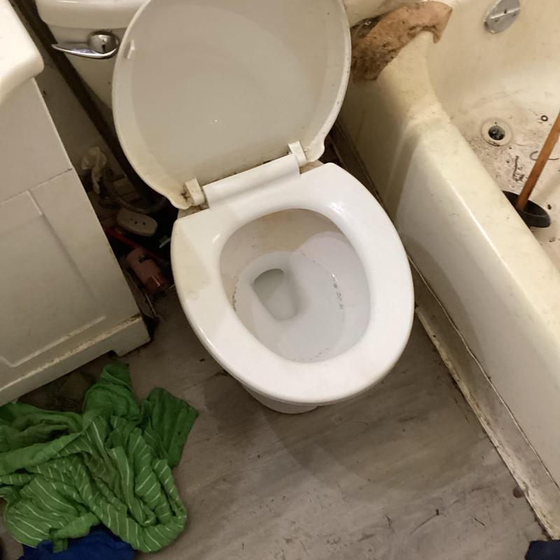 Toilet bowl with sewer line unclogging tools nearby