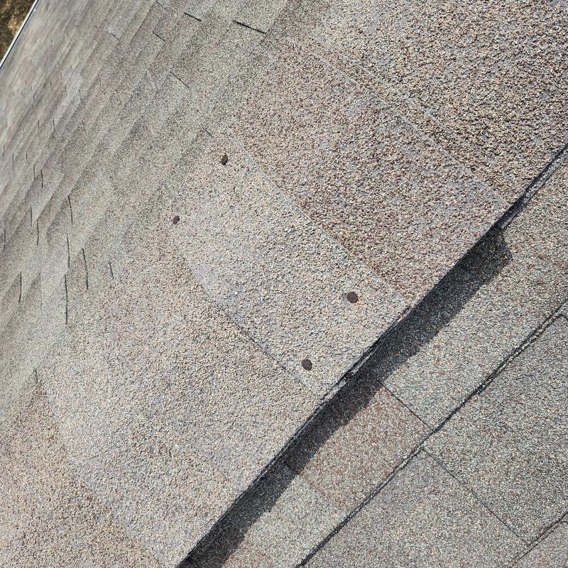 Old asphalt roof shingles with granular loss and brittleness