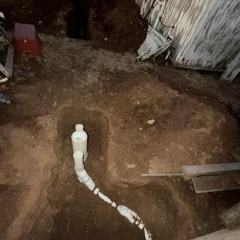 Sewer cleanout installation in dirt near building exterior