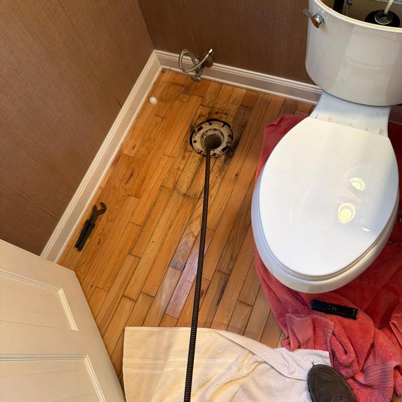 Toilet flange with plumbing snake in bathroom floor