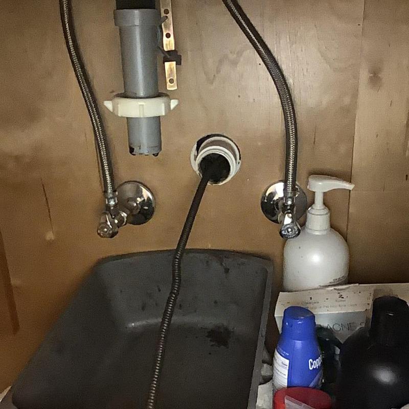 Bathroom sink plumbing supply lines and drain under cabinet