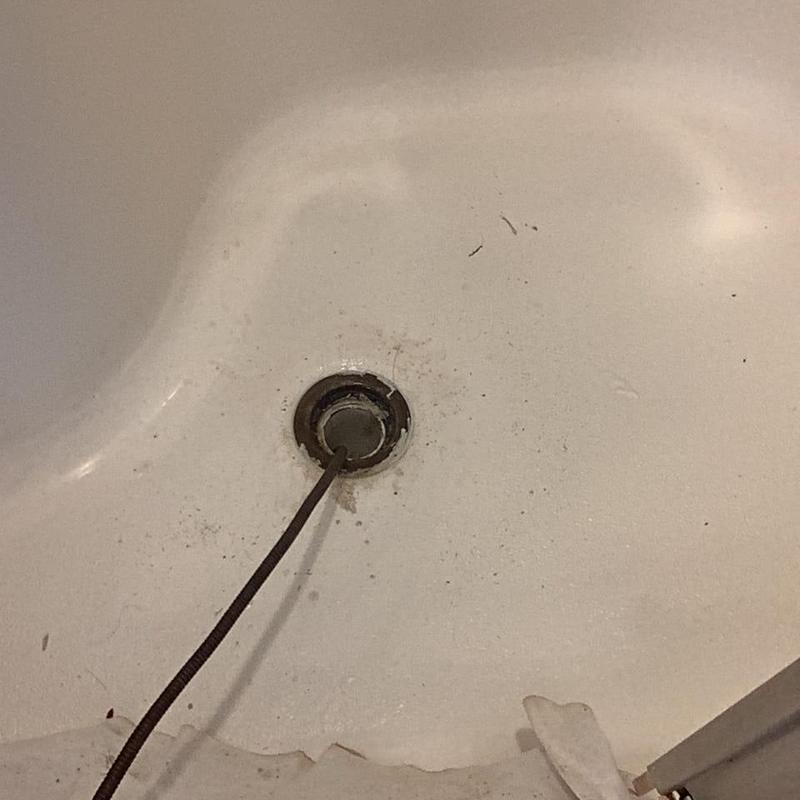 Shower drain with snake tool inside drain opening