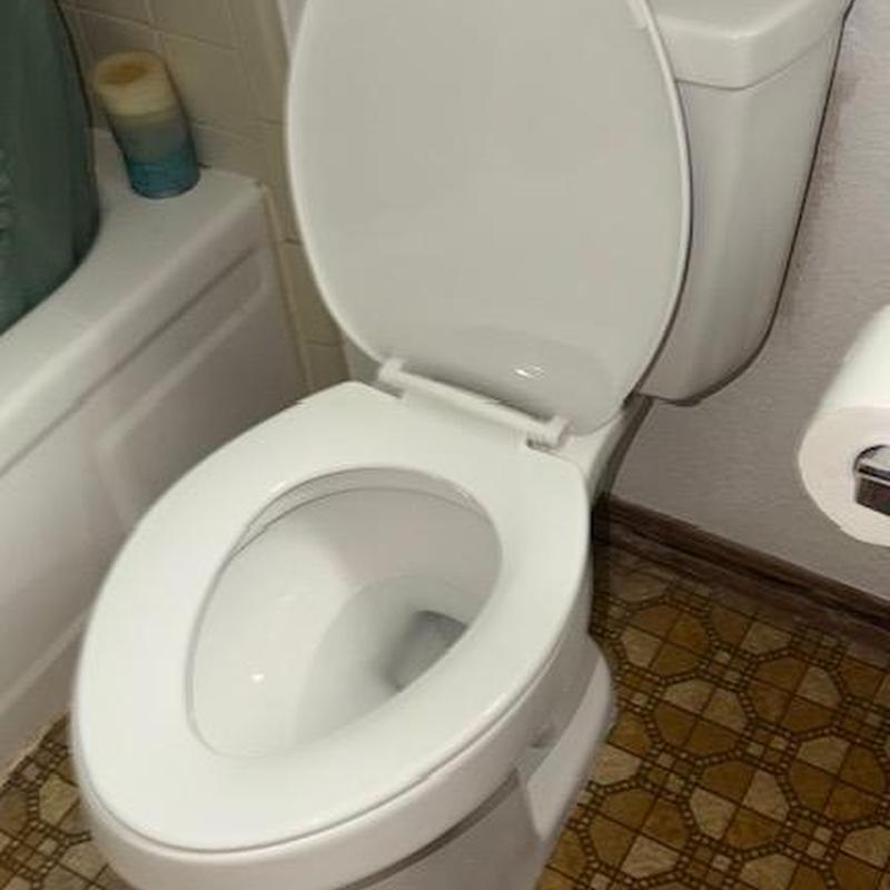 Toilet with open lid in bathroom near bathtub