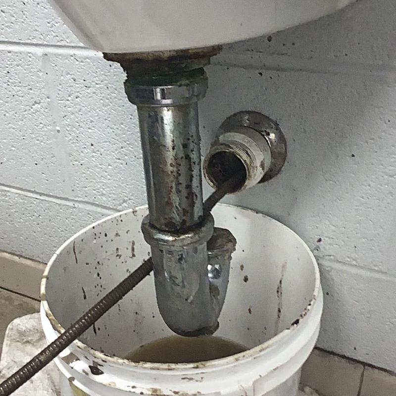 Sink drain trap with cleaning snake and bucket