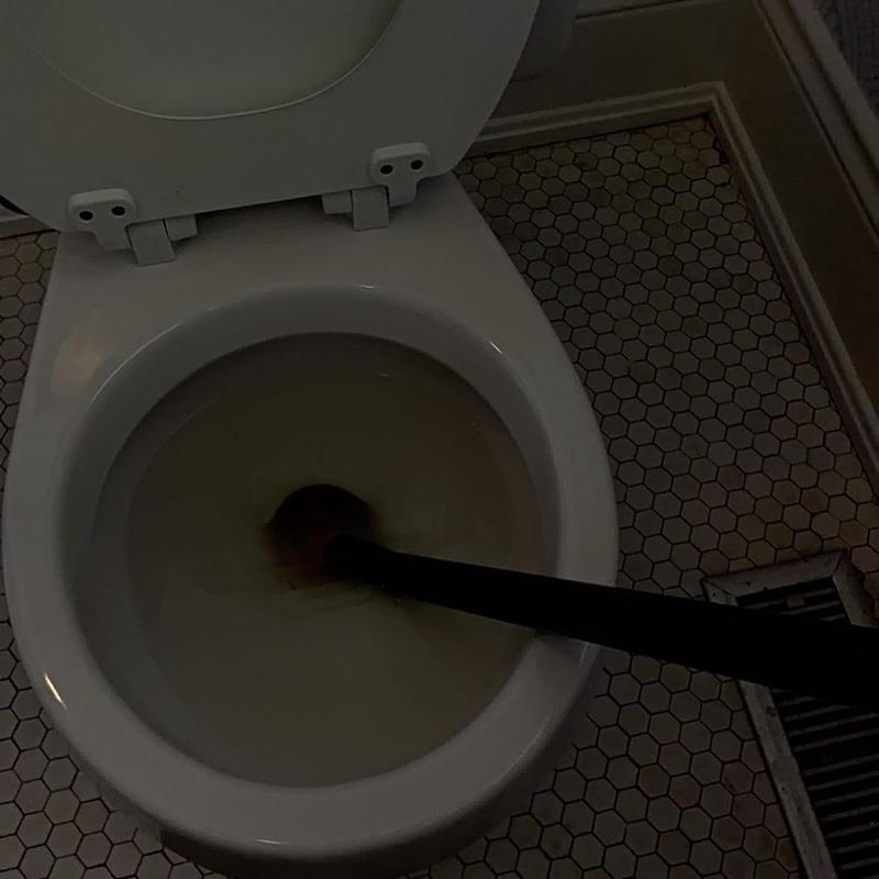 Hallway toilet clog with auger tool in use