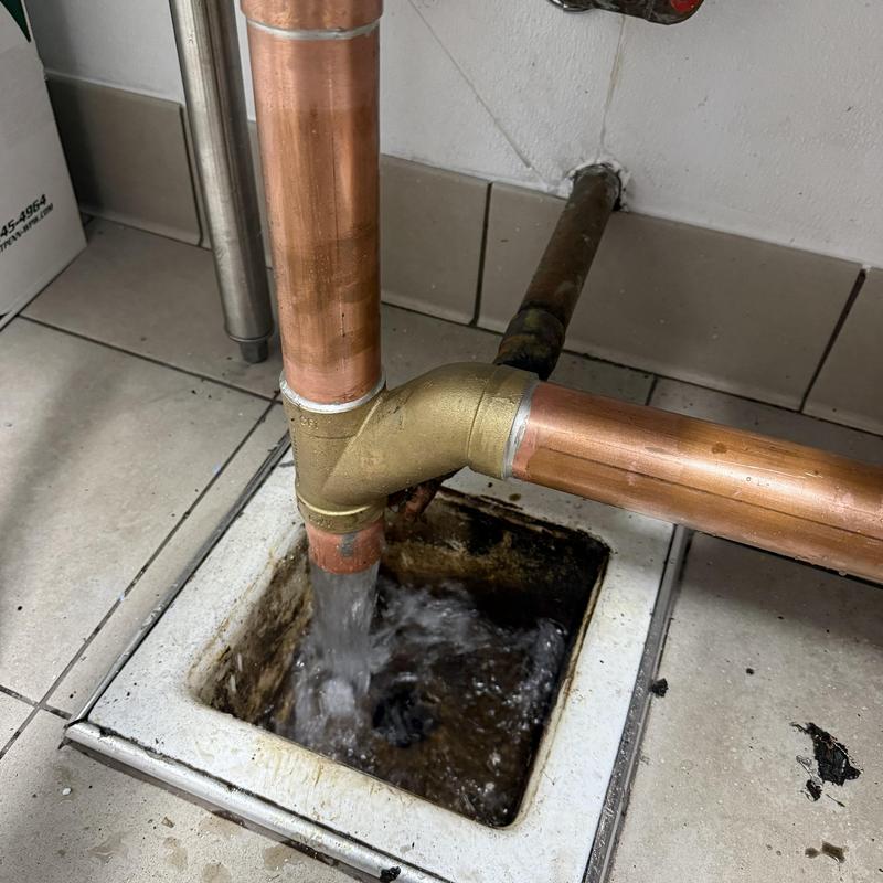 Copper floor drain pipe with flowing water in commercial space