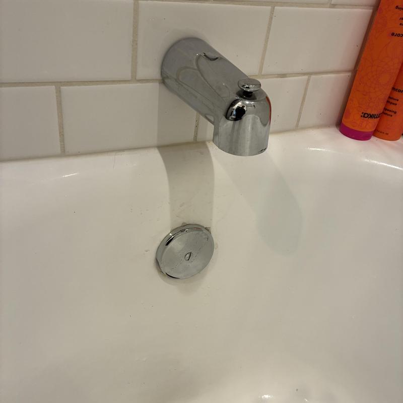 Bathtub drain and spout with tiled wall background
