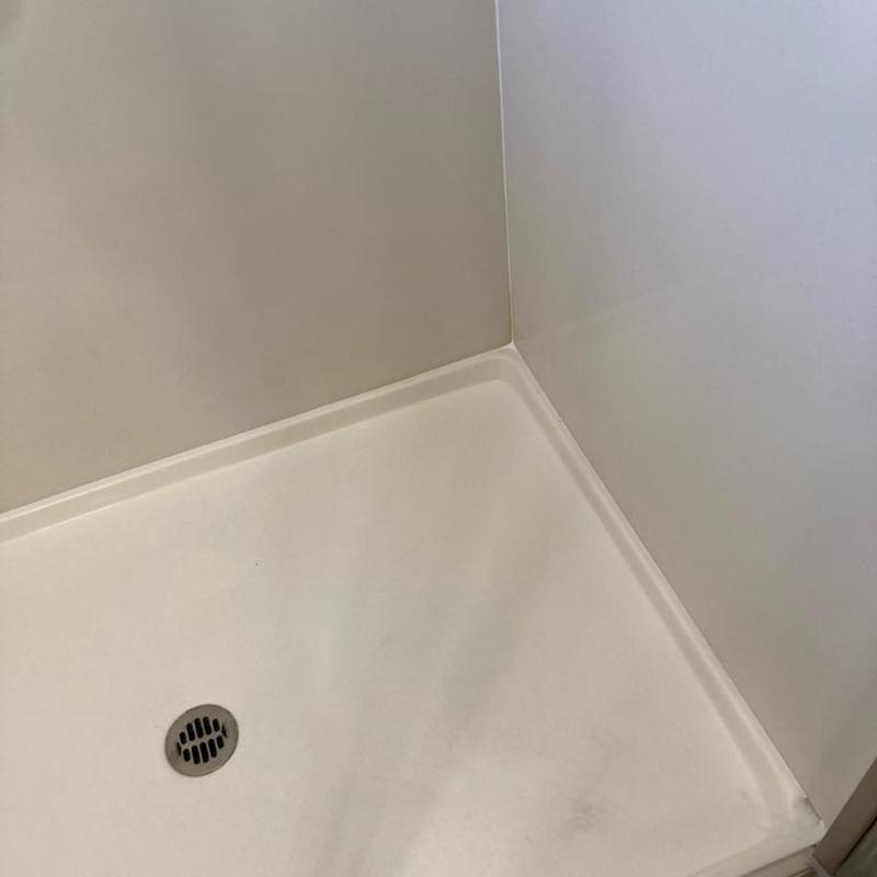 Master shower corner with clean caulking and drain