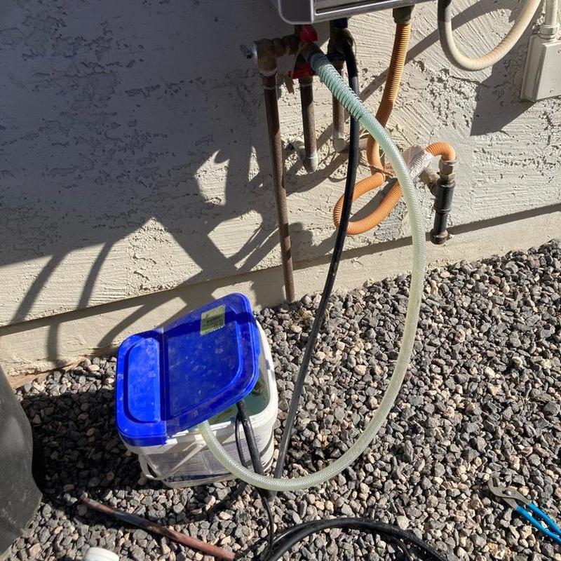 Tankless water heater flushing setup with hoses outdoors