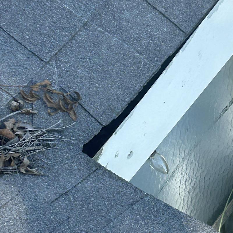 Roof shingles damaged with debris near flashing edge