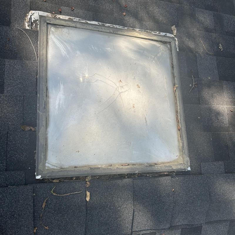 Skylight window on asphalt shingle roof with cracks