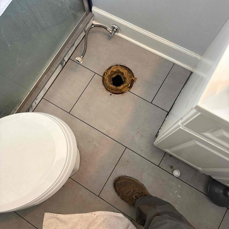 Toilet flange with exposed drain hole and tiled floor