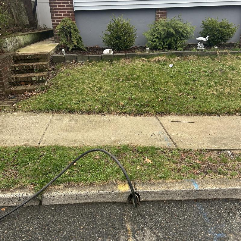 Sewer cleanout jetting hose in curb drainage access Sewer cleanout jetting hose in curb drainage access